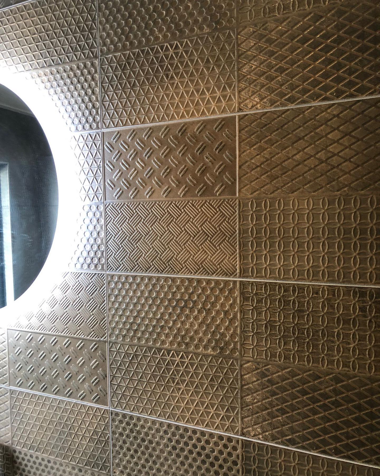 Wand met reliëftegels en een ronde lichtspiegel
