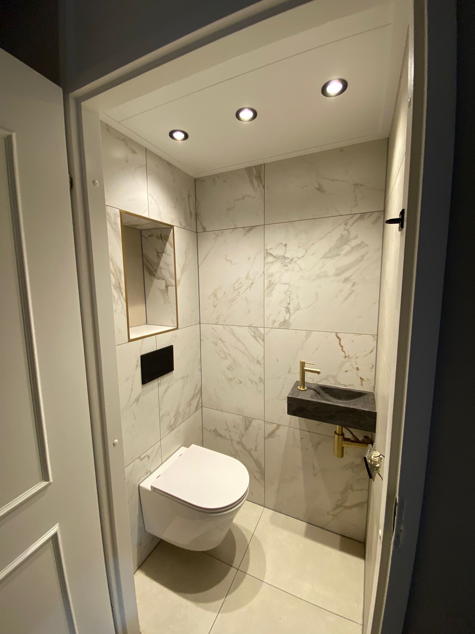 Toilet met marmerlook tegels en een inbouwnis