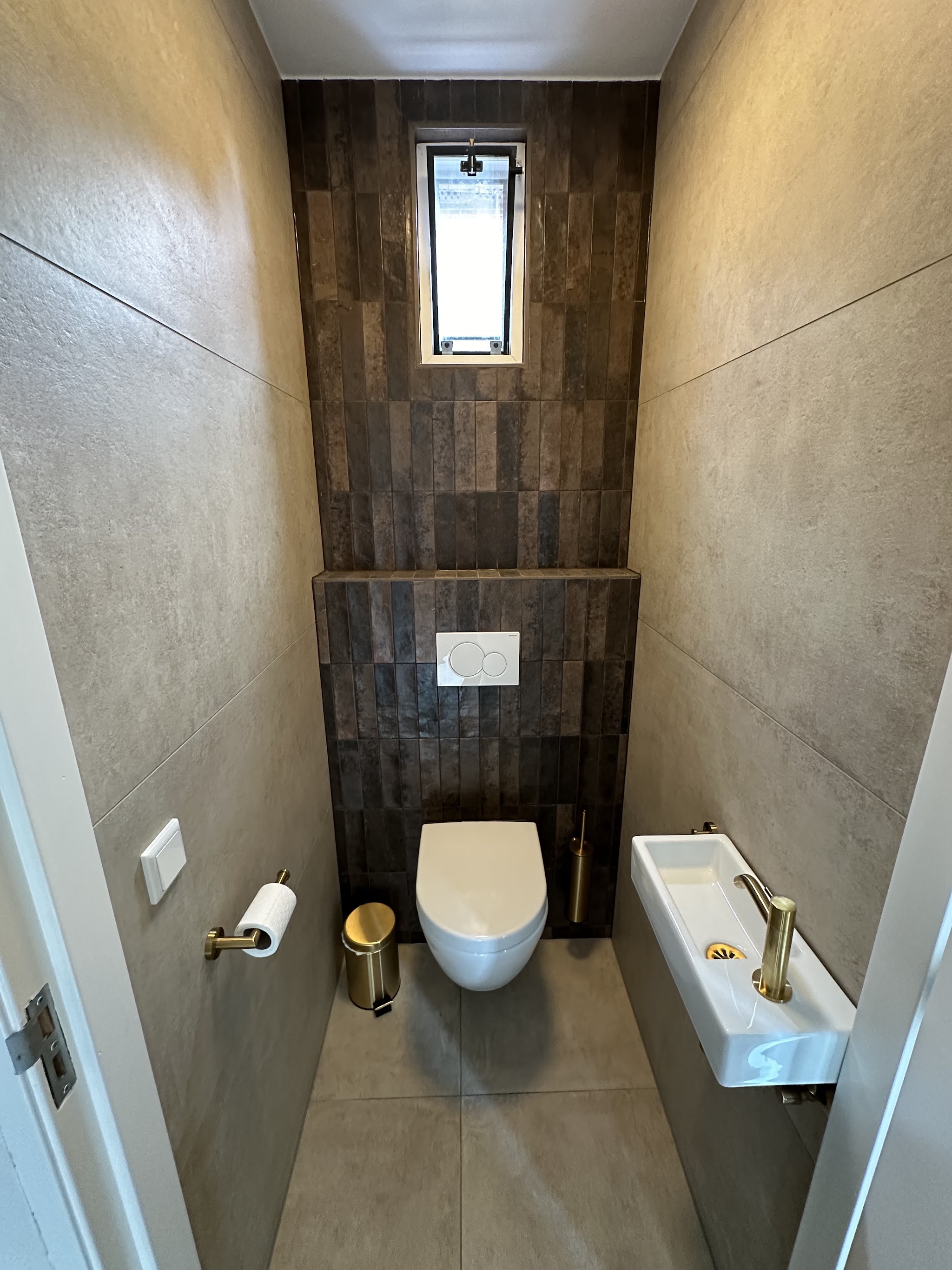 Toilet met betonlook wandtegels en een houtlook strip