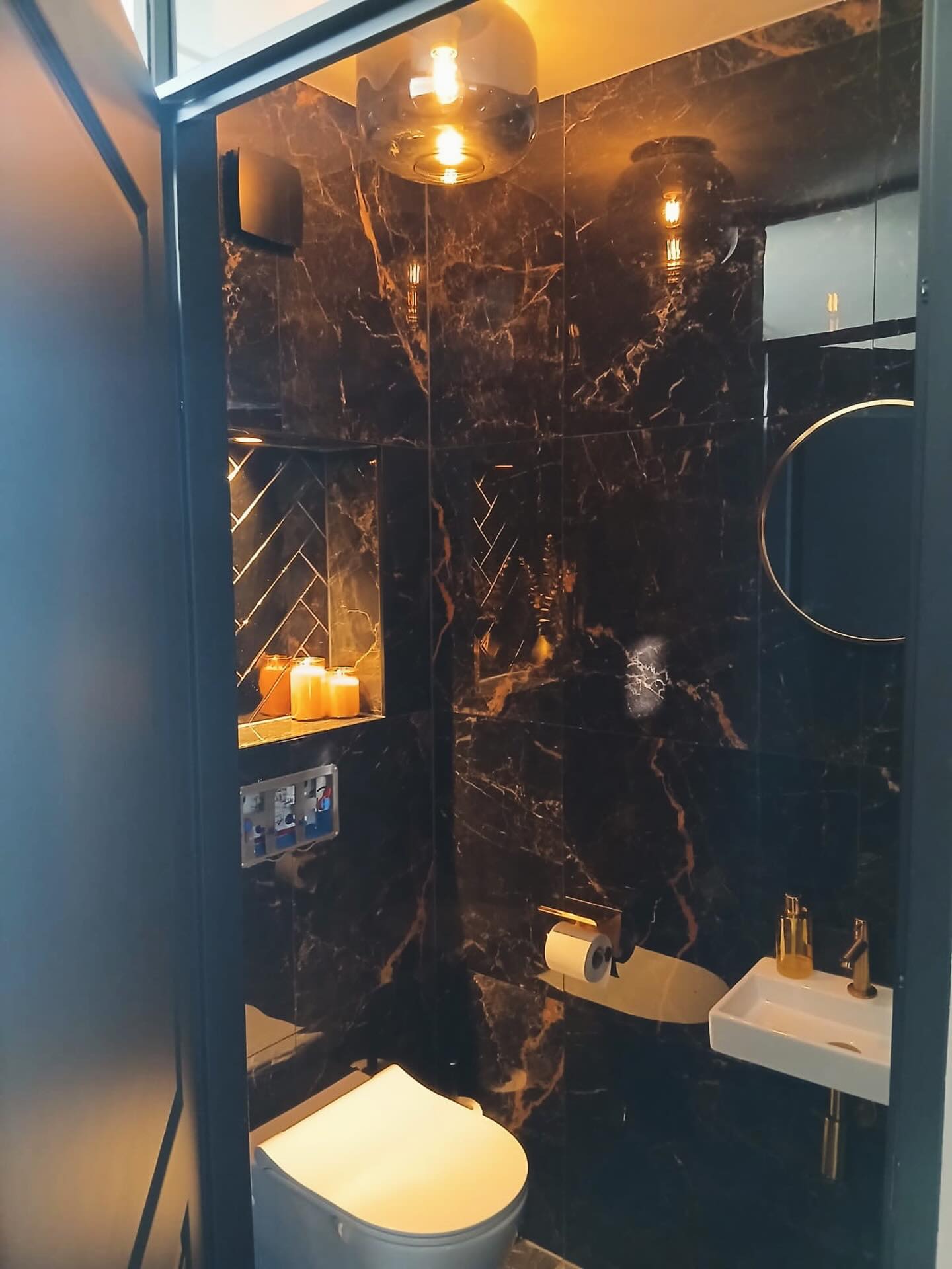 Toilet met zwart marmerlook tegelwerk en warme verlichting