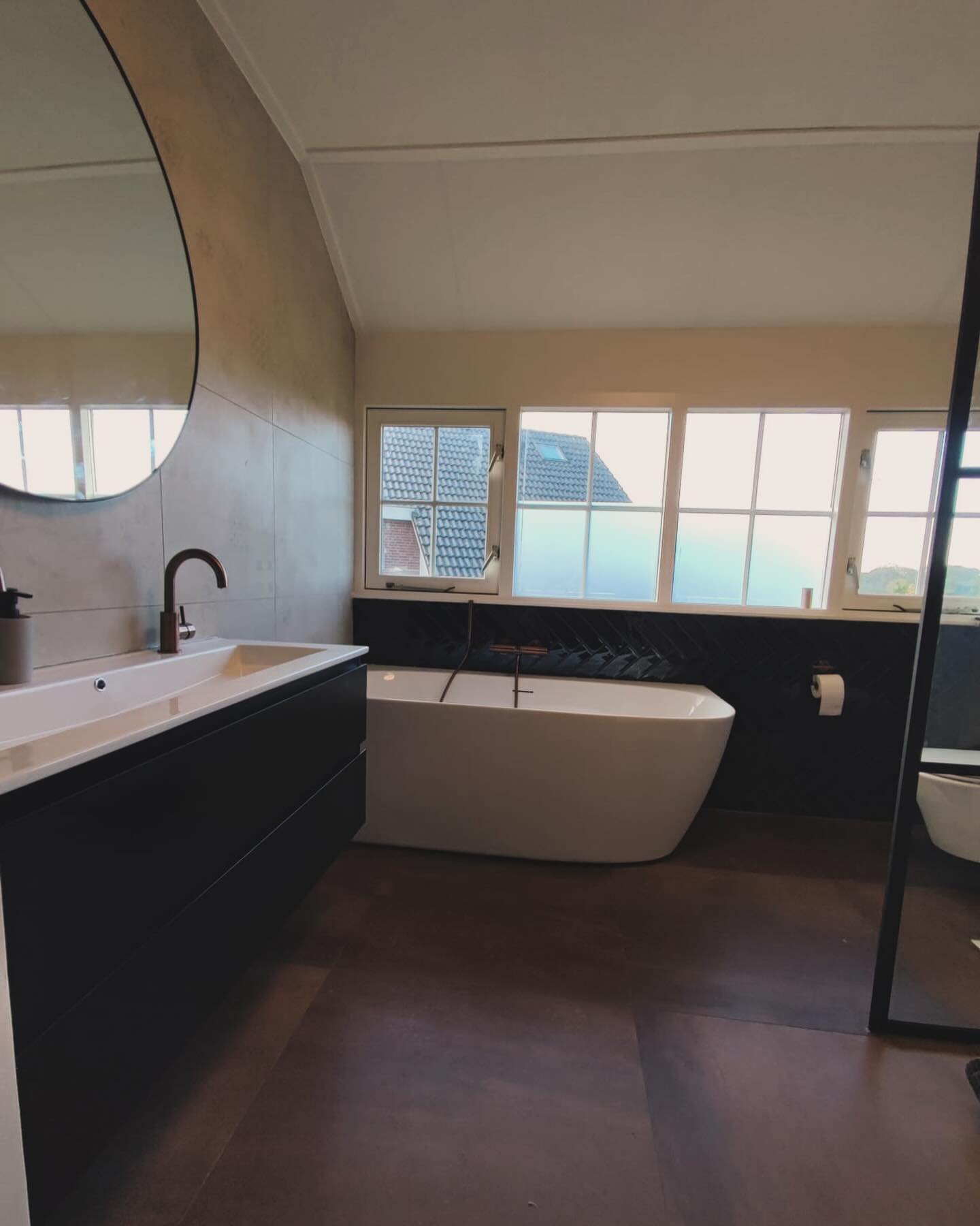 Badkamer onder een schuin dak met een vrijstaand bad