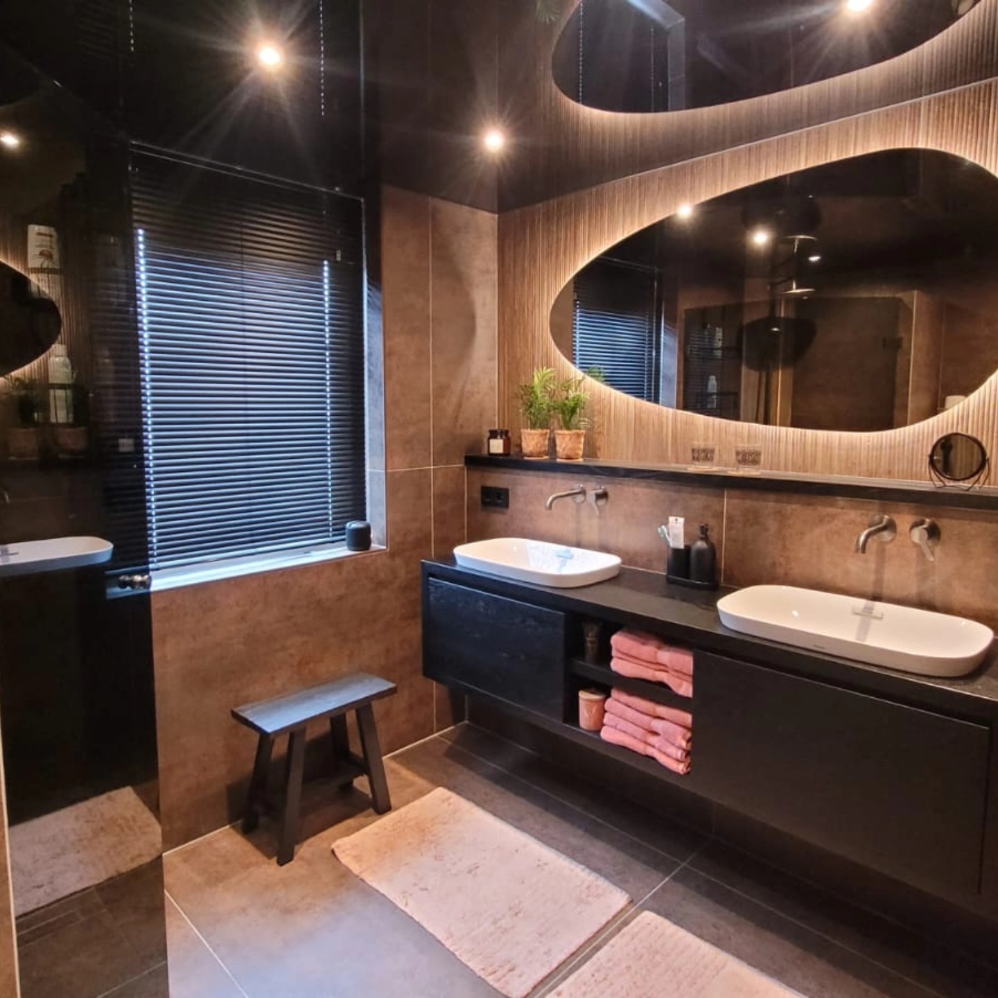 Badkamer met een ovale lichtspiegel en twee wastafels
